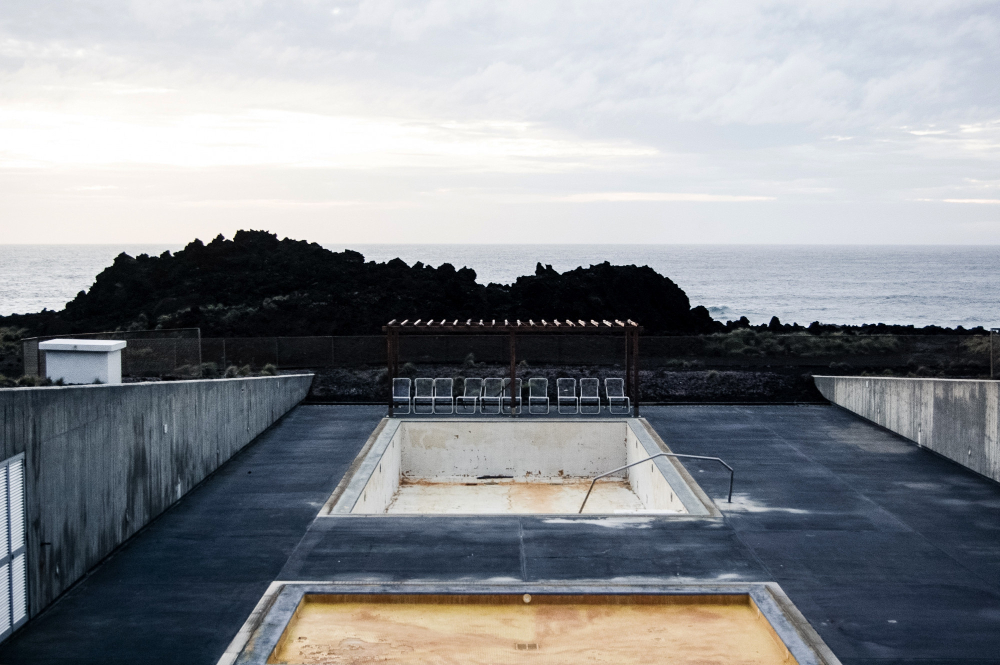 empty-pool-with-chairs-near-cliff-sea