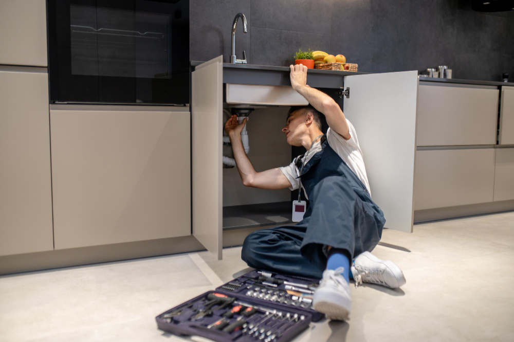 household-repair-middle-aged-man-inspecting-pipe-touching-hand-sink-stylish-modern-kitchen